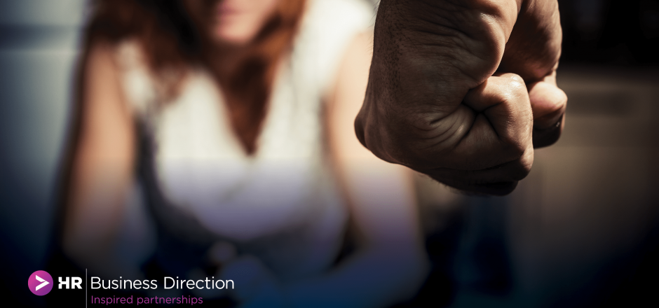 Scene of domestic violence, a mans clenched fist, in front of a woman